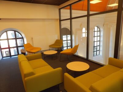 aménagement d'espaces et agencement de mobilier pour le Collegium de Bayeux : table de réunion, chaises empilables, sièges de conférence, canapé lounge, bar central
