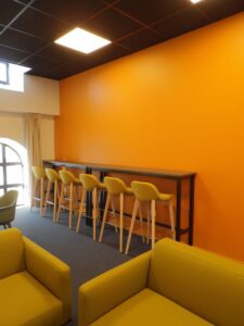 aménagement d'espaces et agencement de mobilier pour le Collegium de Bayeux : table de réunion, chaises empilables, sièges de conférence, canapé lounge, bar central