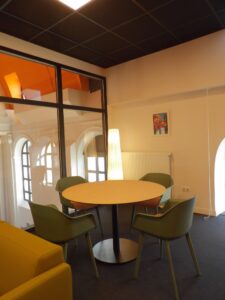 aménagement d'espaces et agencement de mobilier pour le Collegium de Bayeux : table de réunion, chaises empilables, sièges de conférence, canapé lounge, bar central