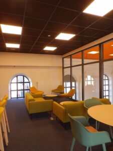 aménagement d'espaces et agencement de mobilier pour le Collegium de Bayeux : table de réunion, chaises empilables, sièges de conférence, canapé lounge, bar central