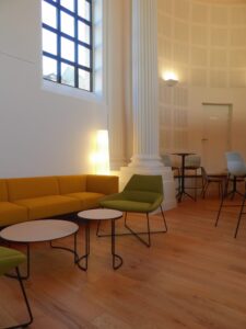 aménagement d'espaces et agencement de mobilier pour le Collegium de Bayeux : table de réunion, chaises empilables, sièges de conférence, canapé lounge, bar central