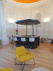 aménagement d'espaces et agencement de mobilier pour le Collegium de Bayeux : table de réunion, chaises empilables, sièges de conférence, canapé lounge, bar central