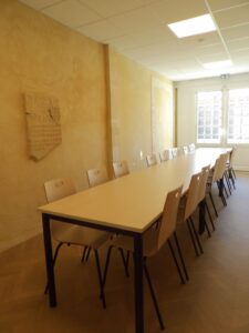 aménagement d'espaces et agencement de mobilier pour le Collegium de Bayeux : table de réunion, chaises empilables, sièges de conférence, canapé lounge, bar central